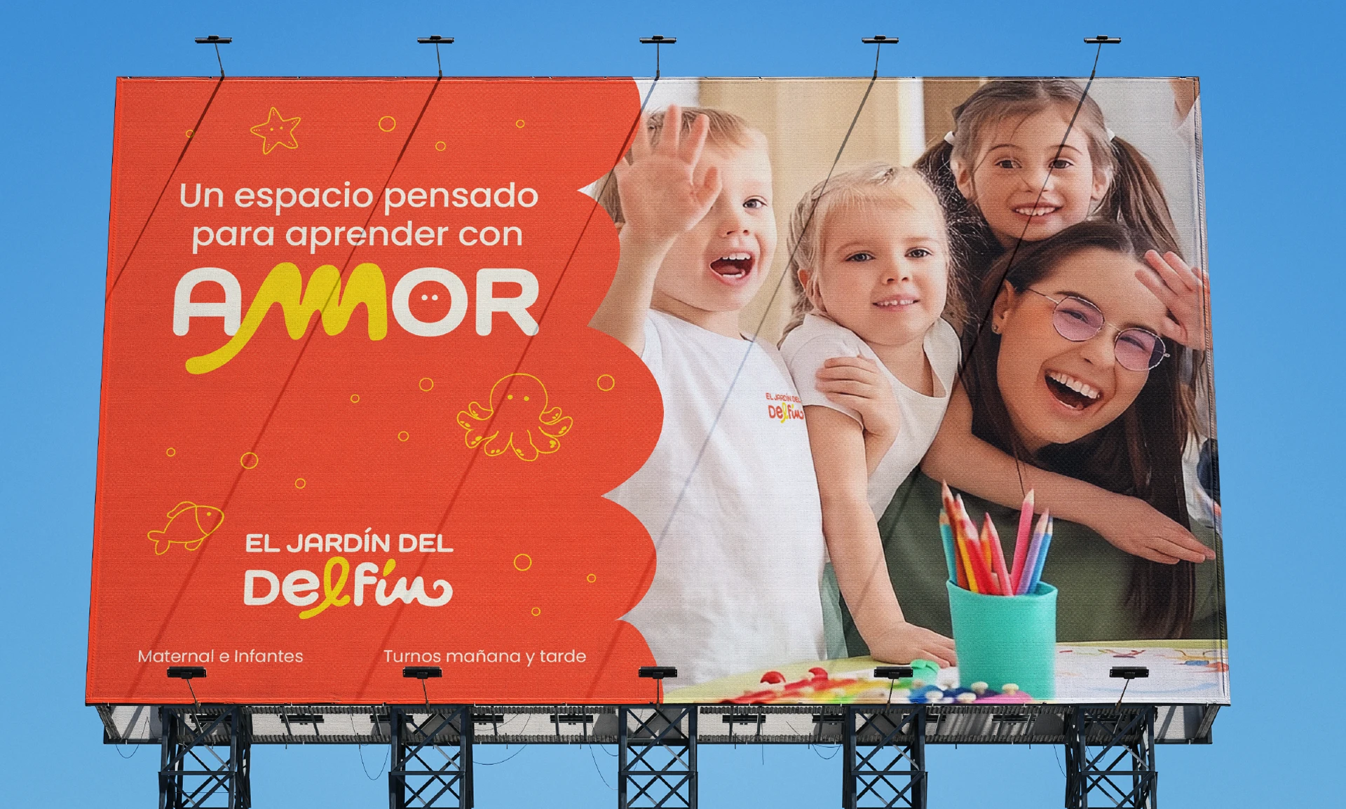 Valla publicitaria de El Jardín del Delfín con una composición colorida, fotografías de niños y un mensaje sobre aprender con amor.